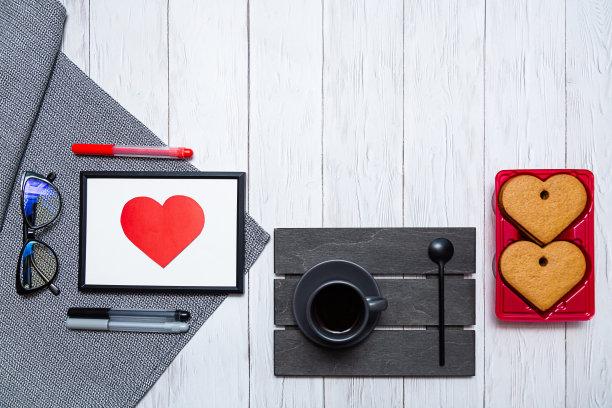 情人节的概念。一杯咖啡，心形的姜饼饼干，眼镜和彩色笔放在一张桌子上。图片下载