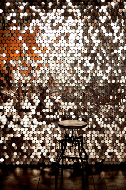 金属底座上的高凳子，映衬着带有亮片的墙壁背景。眩光反射在地板上。迷人的设计图片下载