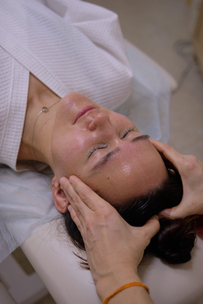 一个闭着眼睛的女孩的头。按摩师的手做头部按摩。图片下载