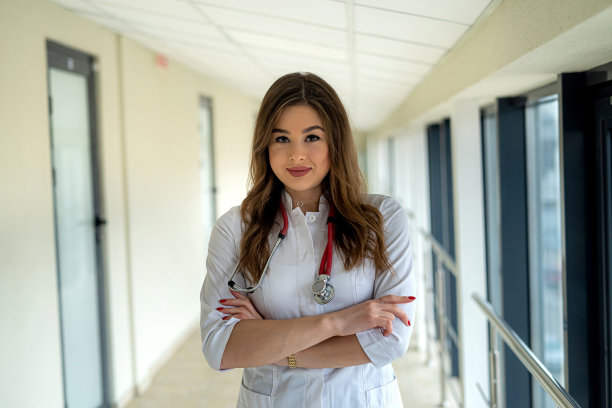 美丽的微笑护士在白色制服与听诊器看着相机的肖像图片下载