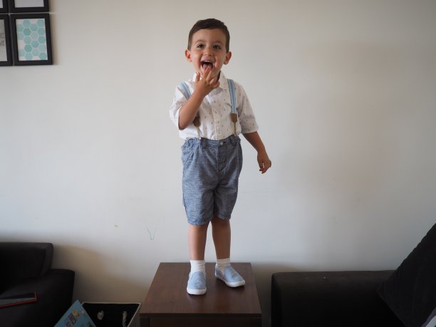 小男孩穿着蓝白相间的衣服站在桌子上图片下载