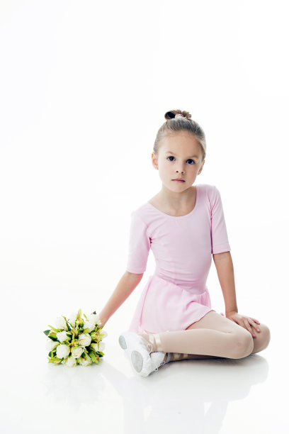 一个小芭蕾舞者在白色的背景和一束花摆姿势图片下载