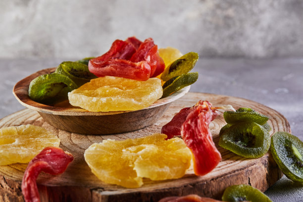 干果：木板和木盘上的黄色蜜饯菠萝圈、红色木瓜和绿色猕猴桃图片下载