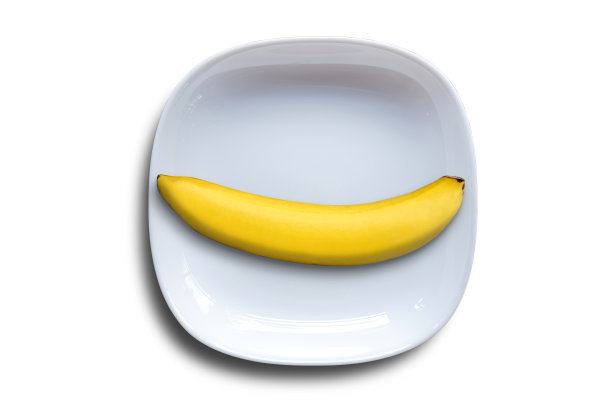 单根香蕉放在白色陶瓷板上，在白色背景上有剪切路径。图片下载