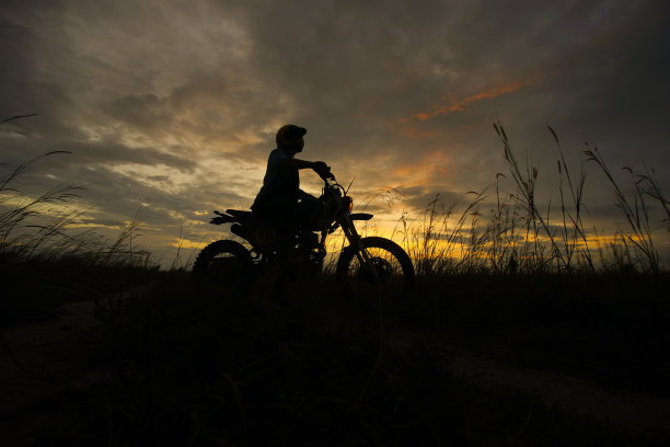 日落时分，一个骑摩托车的男人的剪影图片下载