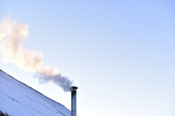 铁制烟囱在冬天的屋顶上冒着烟图片下载