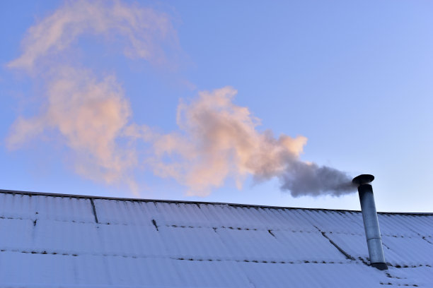 铁制烟囱在冬天的屋顶上冒着烟图片下载