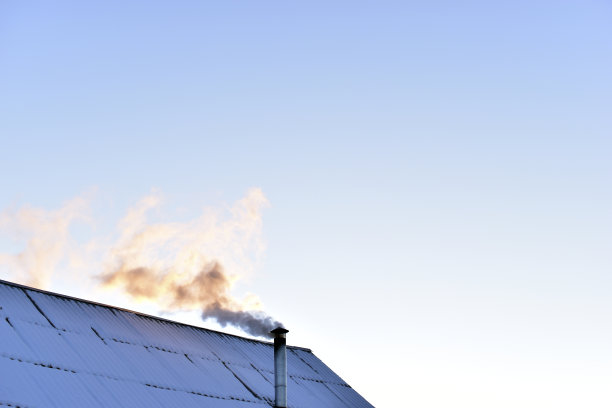 铁制烟囱在冬天的屋顶上冒着烟图片下载