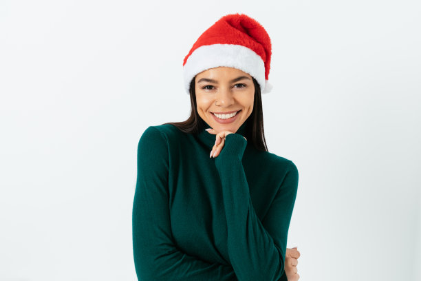 美丽的微笑年轻的黑发女人在圣诞老人的帽子和绿色高领图片下载
