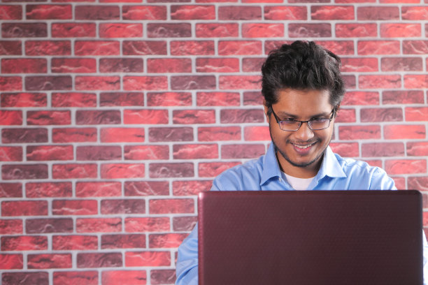 快乐的年轻亚洲人在笔记本电脑上工作与拷贝空间图片下载