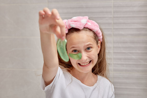 一个漂亮的年轻女孩手里拿着绿色的凝胶眼罩。图片下载