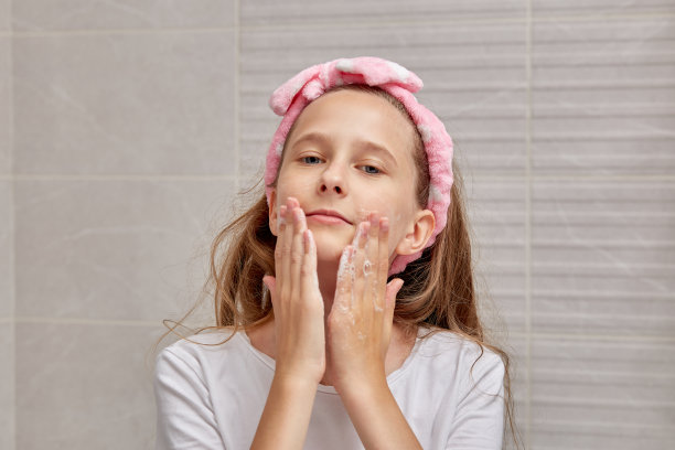 金发女孩用洗面奶和泡沫洗脸。图片下载