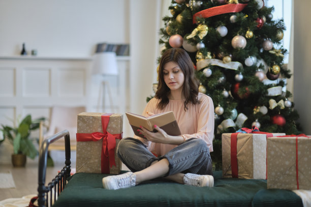 漂亮的年轻女士拥抱纸书的照片。圣诞假期和人们概念快乐的年轻女子用铅笔和笔记本在家里的床上写卧室图片下载