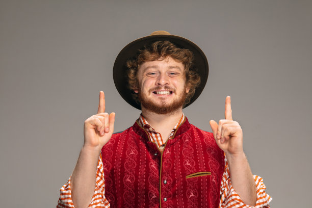 身着传统奥地利或巴伐利亚服装的快乐微笑的男子在灰色的演播室背景上孤立地打手势图片下载