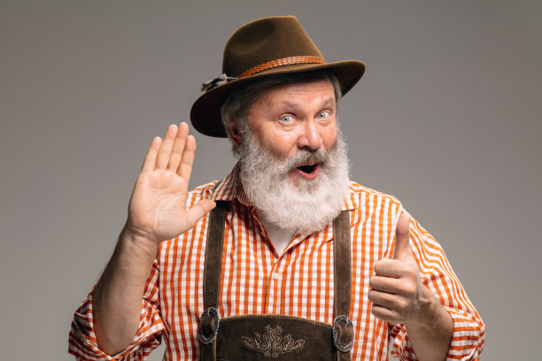 快乐的老人穿着传统的奥地利或巴伐利亚服装手势孤立在灰色的工作室背景图片下载