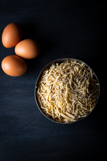 一碗传统的土耳其生面条，背景是鸡蛋。土耳其风格的家用手工面条(eriste)在木背景。图片下载