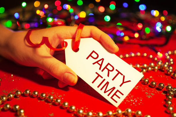 在圣诞和新年假期期间，一名妇女的手拿着一个标签，上面写着“聚会时间”，这是装饰过的圣诞背景。图片下载