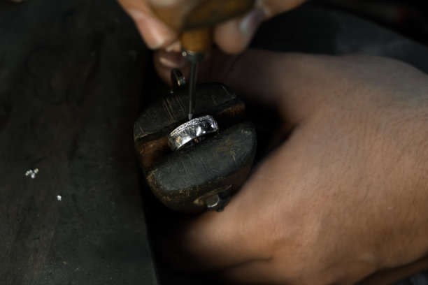 一个金匠将钻石镶嵌在戒指上的手的特写。用专业工具制作首饰图片下载
