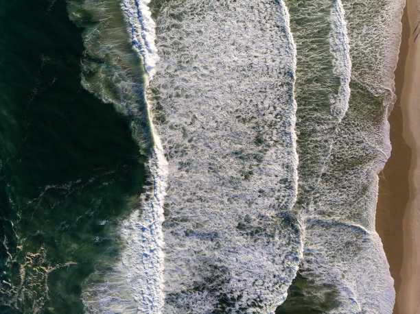 俯视图无人机照片在巴拉达蒂茹卡海滩，里约热内卢de Janeiro，巴西。海浪拍打着白色的浪花，在海面上创造出图案图片下载