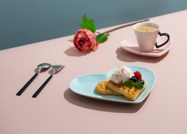 蓝色盘子上的心形比利时华夫饼，粉红色背景上的咖啡。情人节快乐。图片下载