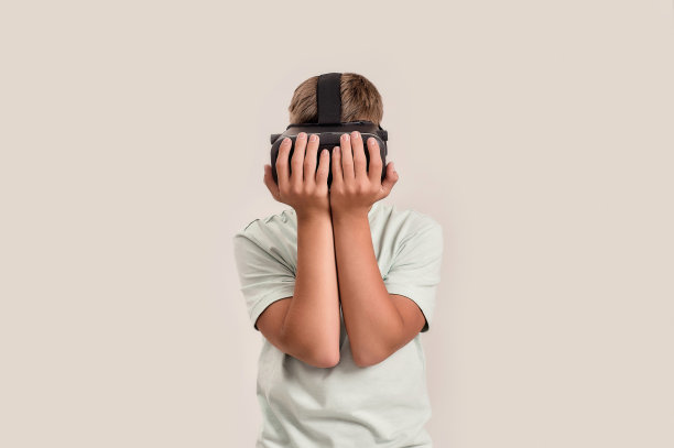 戴着VR眼镜的唐氏综合症少年。特殊儿童体验虚拟现实，孤立地站在白色背景图片下载