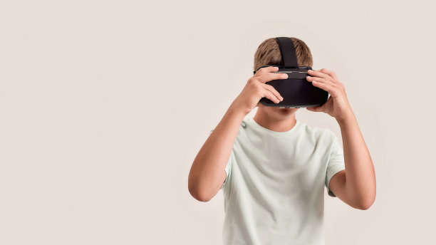 患有唐氏综合症的少年戴着，调整VR眼镜。特殊儿童体验虚拟现实，孤立地站在白色背景图片下载
