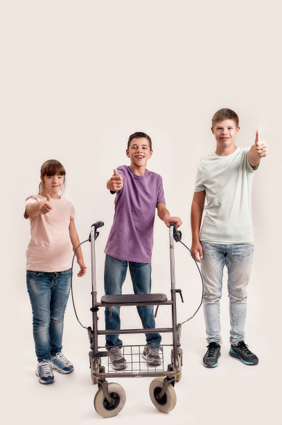 3名患有唐氏综合症和脑瘫的残疾儿童在白色背景下孤立地站在一起，他们微笑着竖起大拇指图片下载
