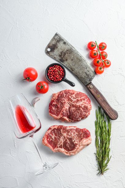 有机顶级牛排，生牛肉调味料，迷迭香，石榴，玫瑰酒杯和切肉刀。白色纹理背景。前视图。图片下载