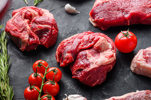 生牛肘眼卷牛排切块，配香草、调味料放在黑色的桌子上，侧视。图片下载