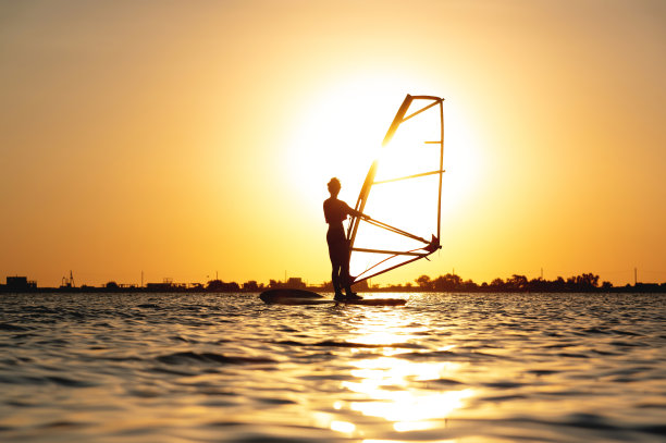 美丽的日落时分，在海湾上冲浪的女人的剪影图片下载