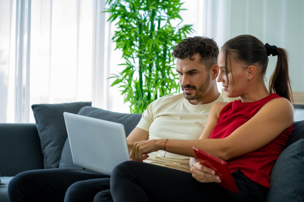 白人商务女性在家用笔记本电脑工作，男朋友在床上图片下载