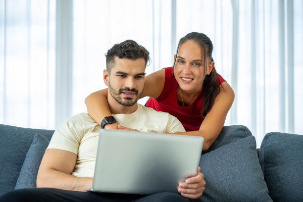 白人商务女性在家用笔记本电脑工作，男朋友在床上图片下载