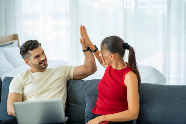 白人商务女性在家用笔记本电脑工作，男朋友在床上图片下载