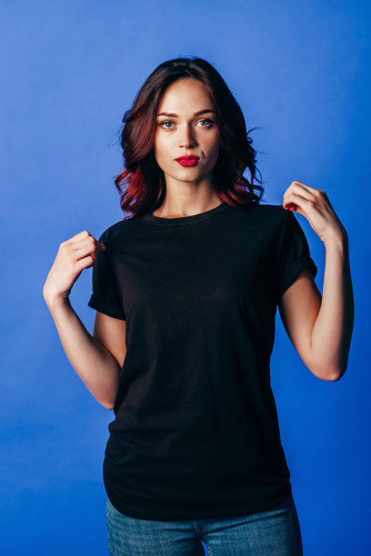 穿着蓝色牛仔裤和黑色t恤的年轻女子的肖像图片下载