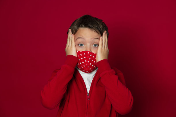 在红色背景前戴着红色面具的酷小男孩图片下载