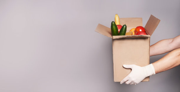 戴着手套的白人手里拿着一盒杂货，快速、安全的食品运送图片下载