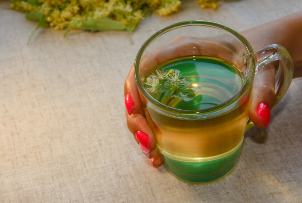 亚麻桌布的背景上，女人手里拿着柠檬茶。图片下载