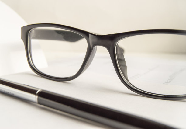 黑白特写的一个静物生活与老花镜和一支笔在桌面上。没有人的办公室内部图片下载