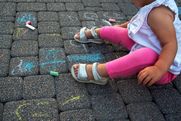 小女孩用粉笔在地上画画。幸福童年的概念。图片下载