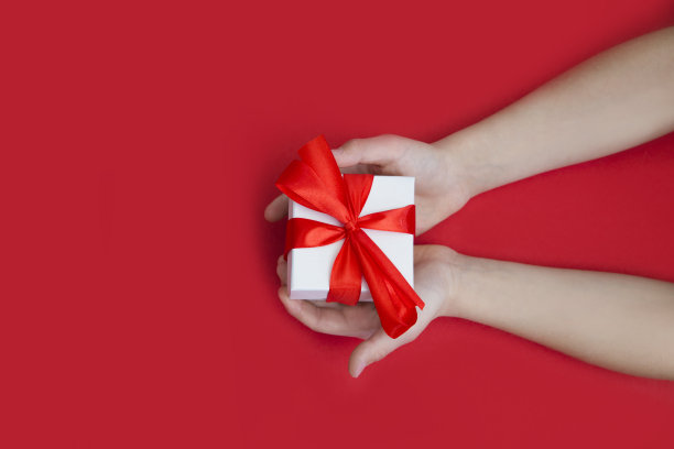 孩子们的手握礼品盒上的红色背景。由母亲节的概念。父亲节。的生日。图片下载