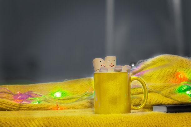 黄色的热饮和融化的有趣的棉花糖雪人。灰色背景。副本的空间。图片下载