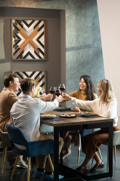 两对年轻愉快友好的夫妇穿着时髦的休闲装，举杯共饮红酒图片下载