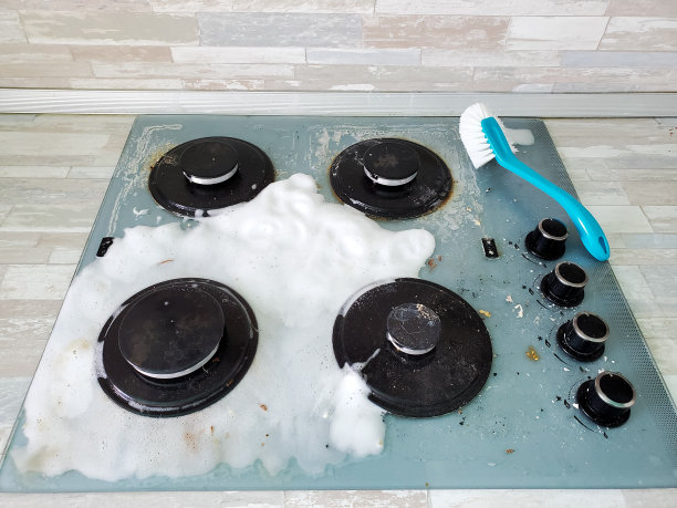 照片上是一个脏兮兮的现代煤气炉，上面覆盖着泡沫，还有一个用来清洁炉子的刷子图片下载