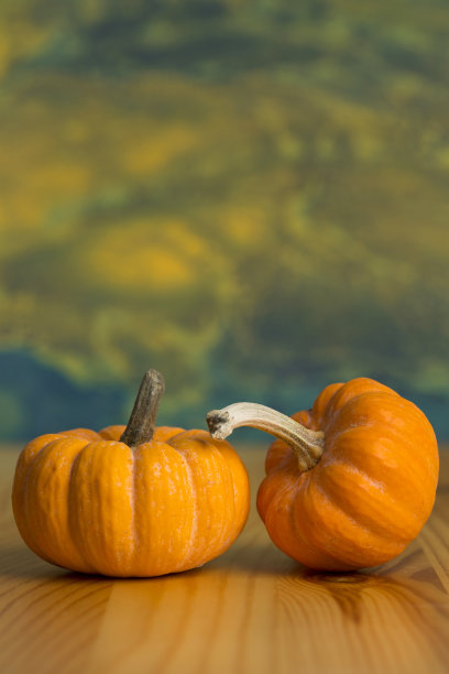 两个橙色的小南瓜孤立地放在木桌上。垂直特写，抽象背景。图片下载