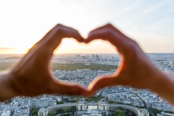 夕阳西下的巴黎，一对夫妇用手做一个心形图片下载