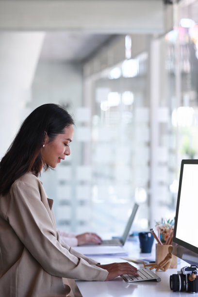 肖像的年轻女性摄影师与电脑在现代办公室工作。图片下载