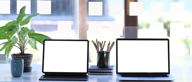 创造性工作空间上的笔记本电脑和数字平板电脑的正面视图。空白屏幕用于图形显示蒙太奇。图片下载