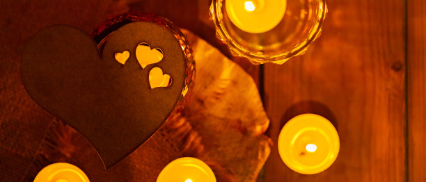 粗麻布和木板上的木心和蜡烛。情人节贺卡，蜡烛和心在模糊的背景。爱情故事的概念。本空间图片下载