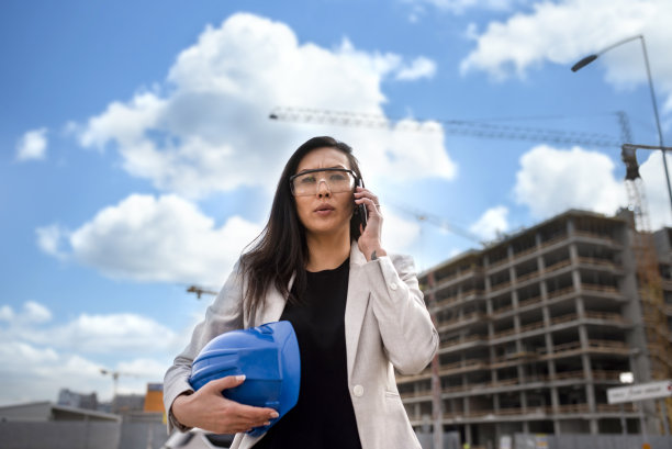 混血女商人在一个建筑工地作为建筑师使用手机库存照片图片下载