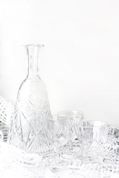 极简主义的静物生活与水晶盘在白色的背景。空的水晶酒瓶和玻璃杯。本空间图片下载